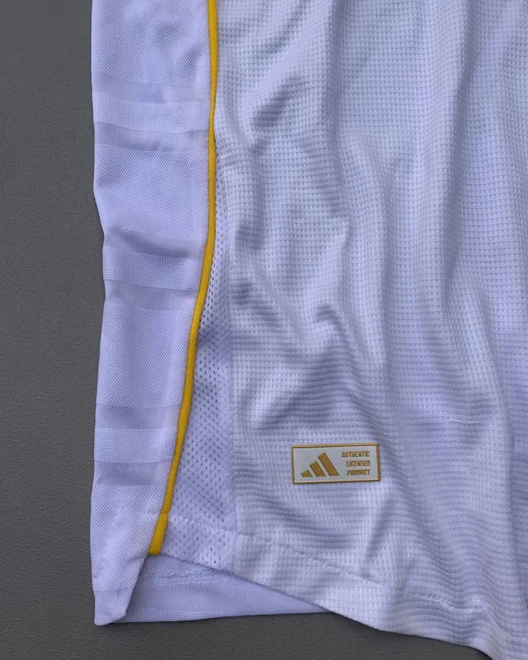 Real Madrid 2025/26 home jersey with classic white design, black adidas stripes, golden-yellow trim, Emirates Fly Better sponsor, and embroidered club crest – official fan and player kit