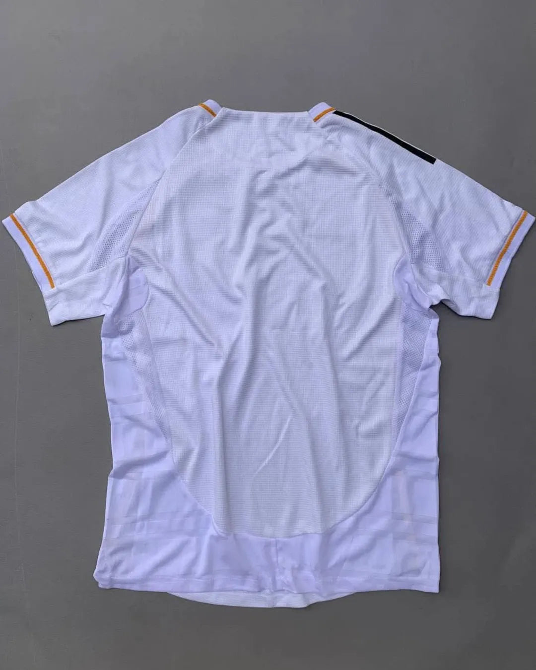 Real Madrid 2025/26 home jersey with classic white design, black adidas stripes, golden-yellow trim, Emirates Fly Better sponsor, and embroidered club crest – official fan and player kit